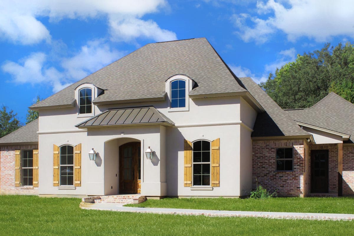 House plan exterior with two stories. Features a gabled roof, arched entryway, dormer windows, and brick and stucco facade.