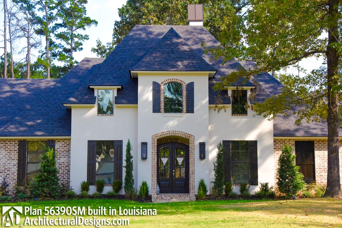 French Provincial house plan exterior with arched entry, dormers, multiple gables, and brick and stucco finishes.