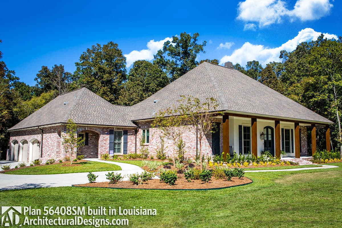 House plan exterior: one-story brick home with a covered porch, arched garage doors, and multiple gables.