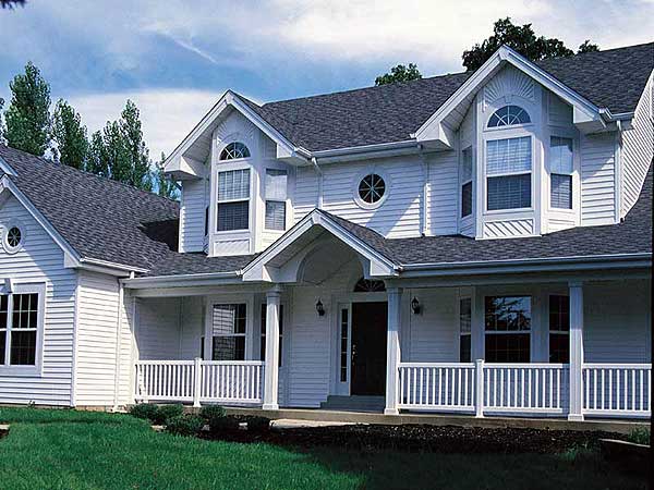House plan exterior: two-story home with wraparound porch, gables, bay windows, and arched dormers.