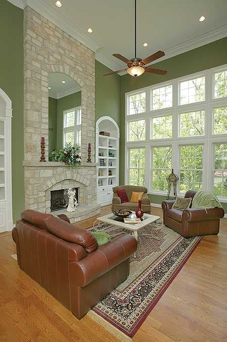 Great room interior rendering with stone fireplace, built-in shelving, and a wall of large windows.