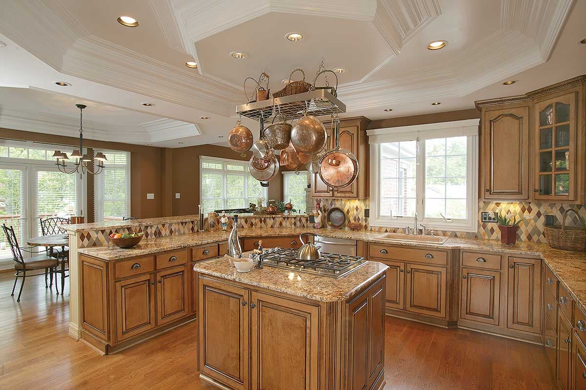 Kitchen with island, granite countertops, wood cabinets, and a decorative multi-level ceiling with pendant lighting.