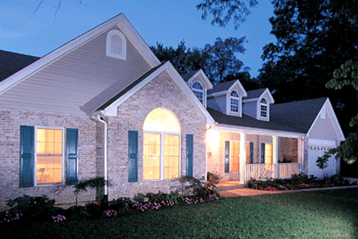 House plan exterior: Two-story Traditional style with brick front, dormer windows, covered porch, and attached garage.