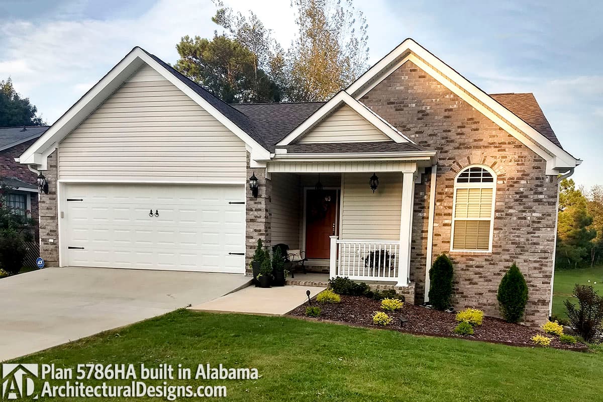 House plan exterior: One-story home with a gabled roof, vinyl siding, brick accents, two-car garage, and covered front porch.