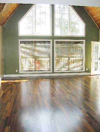 Interior view of a room with vaulted, wood-paneled ceiling, large casement windows, and hardwood floors.