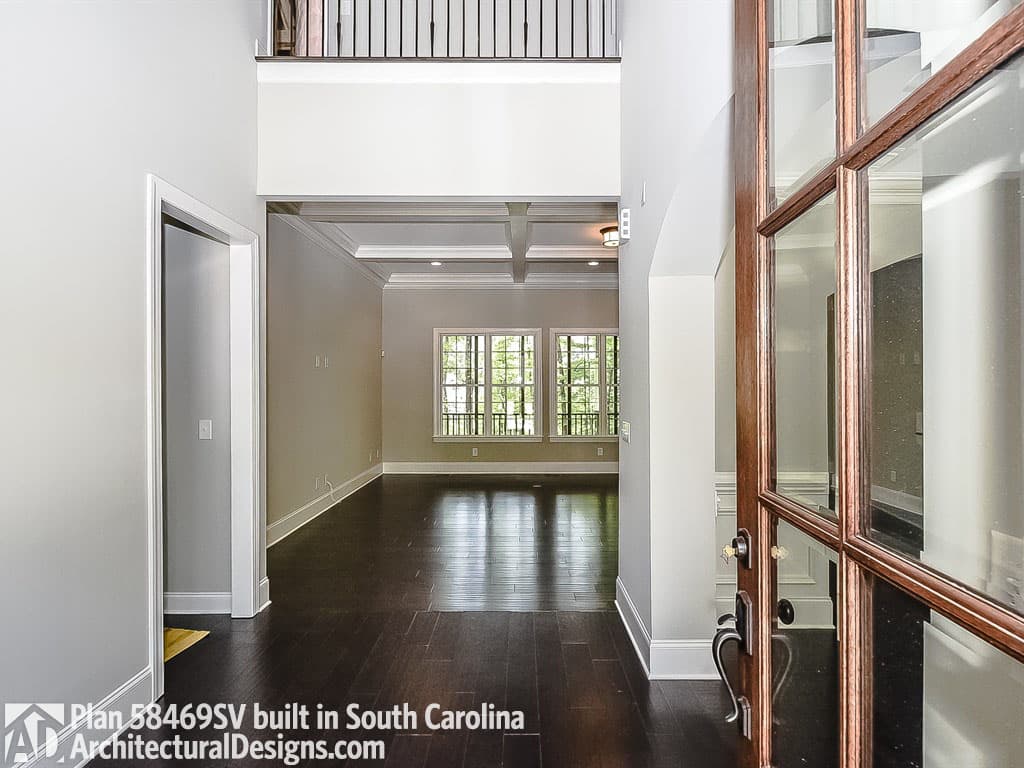 Interior view of house plan 58469SV with coffered ceiling, dark wood floors, and view to large windows.