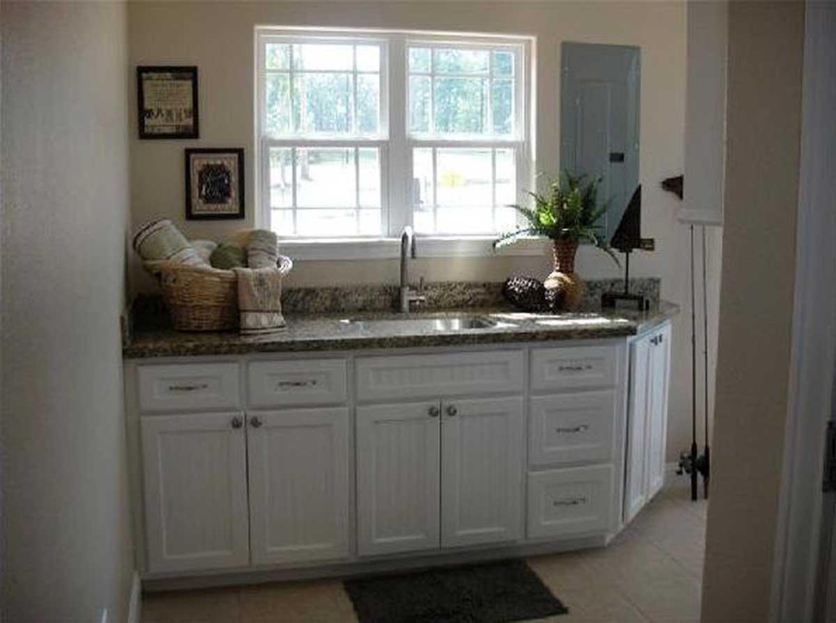 White shaker-style cabinetry with granite countertops and a double-hung window above a sink.