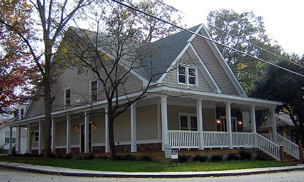 House plan exterior: two-story Modern Farmhouse with wrap-around porch, gables, dormers, and stone foundation.