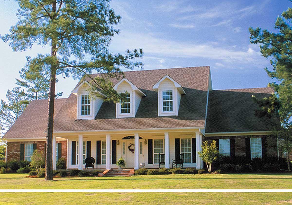 House plan exterior: Two-story Traditional style with prominent covered porch, three front dormers, and brick accents.