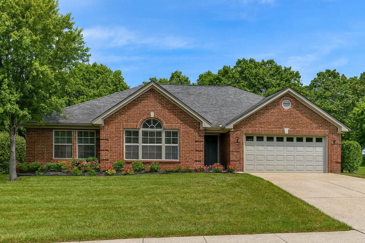 Ranch house plan exterior with brick facade, arched window, and attached two-car garage.