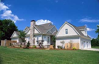 House plan exterior of a two-story Modern Farmhouse with a stone chimney, prominent gables, and a side-entry three-car garage.