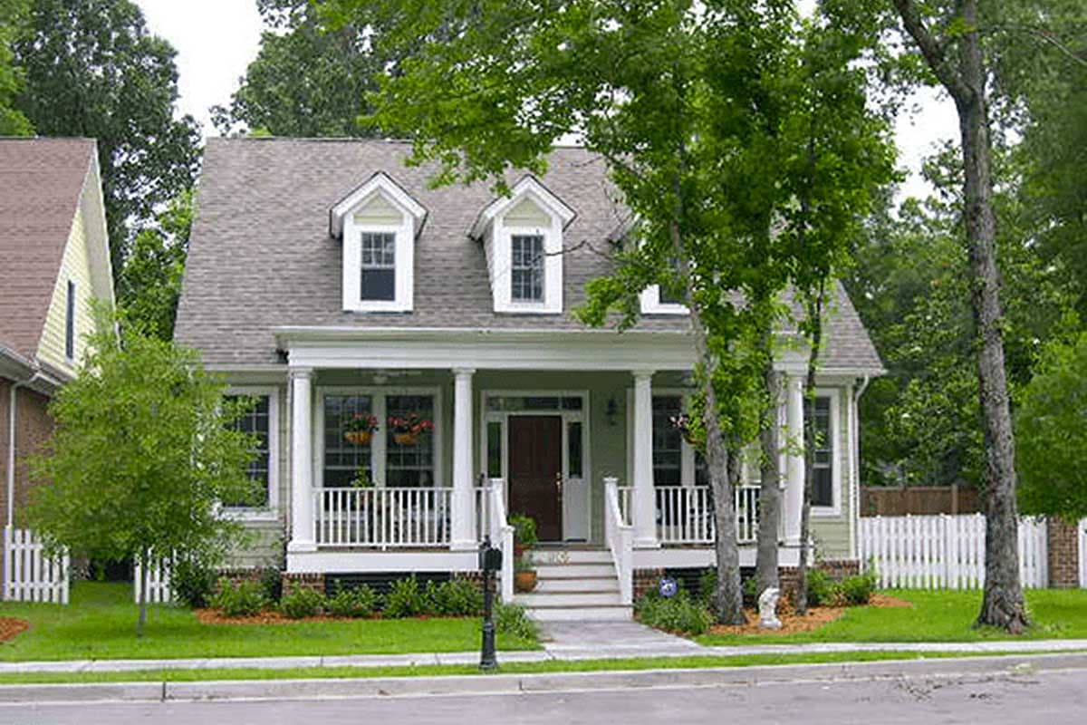 House plan exterior: Two-story home with a covered front porch, white railings, dormers, and columned entry.