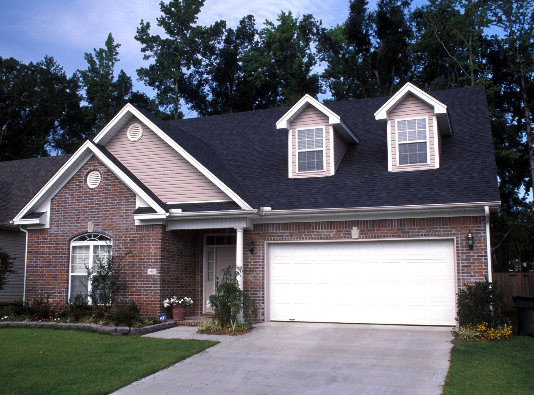 House plan exterior: One-story brick home with gables, two dormers, and an attached two-car garage.