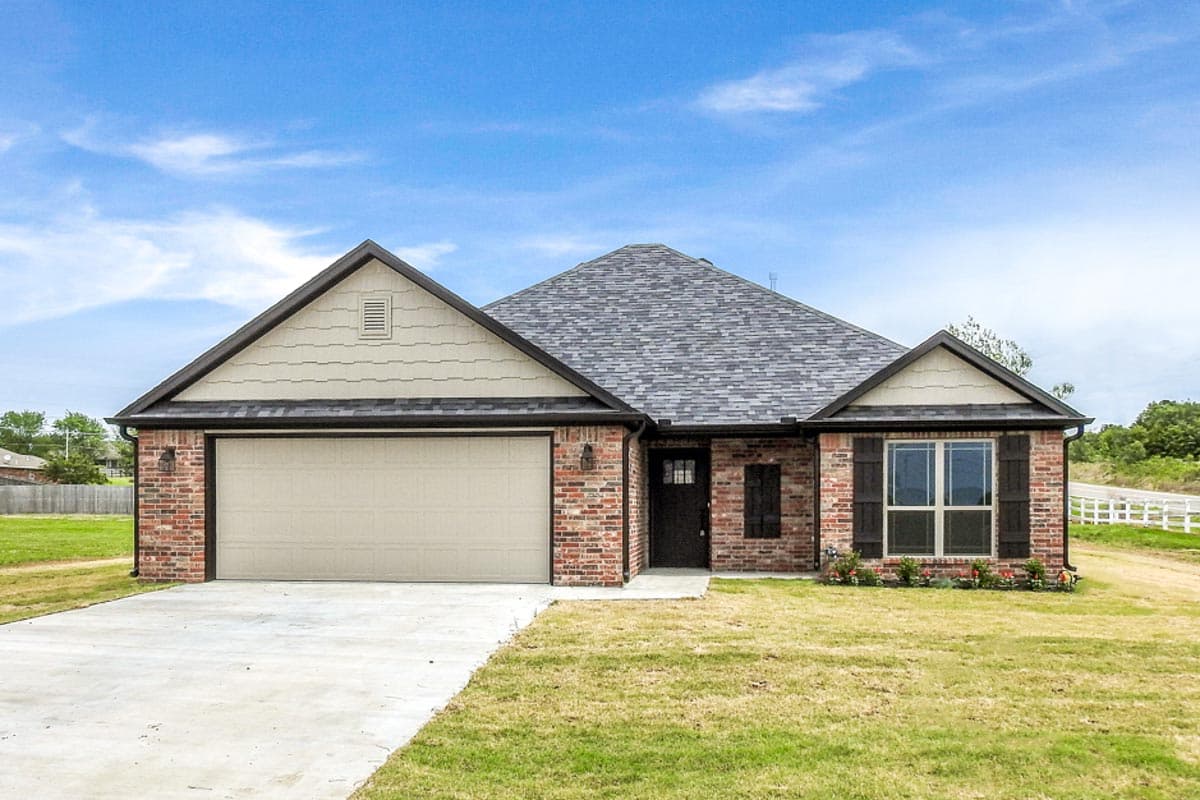 House plan exterior: One-story home with brick facade, asphalt shingle roof, attached garage, gabled dormer, and dark shutters.
