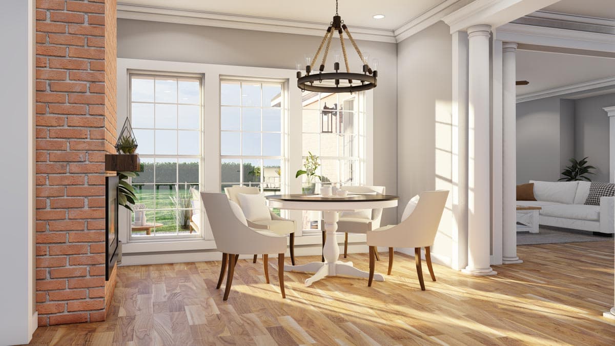 Dining area with brick fireplace, round table, chairs, and view to living room with sofa.