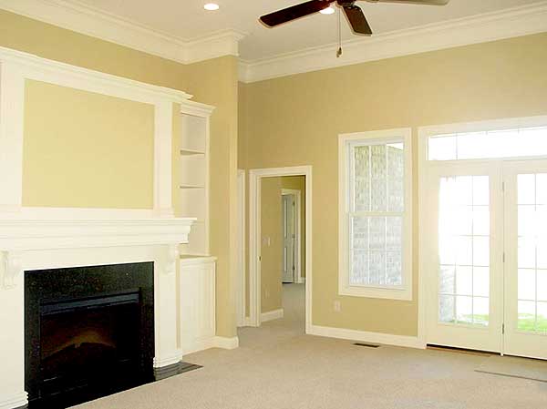 Living room with fireplace, built-in shelving, vaulted ceiling, ceiling fan, and French doors.