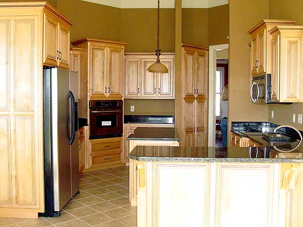 Kitchen with light wood cabinets, stainless steel refrigerator, double ovens, and granite countertops.