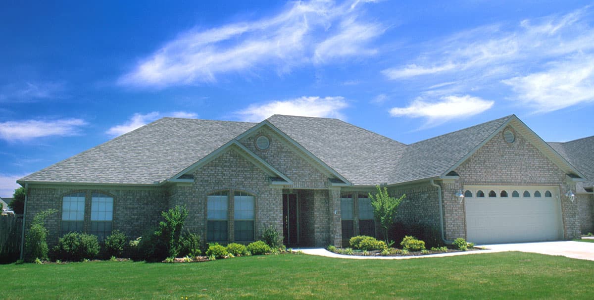 House plan exterior of a one-story brick home with a gabled entrance, arched windows, and a three-car garage.