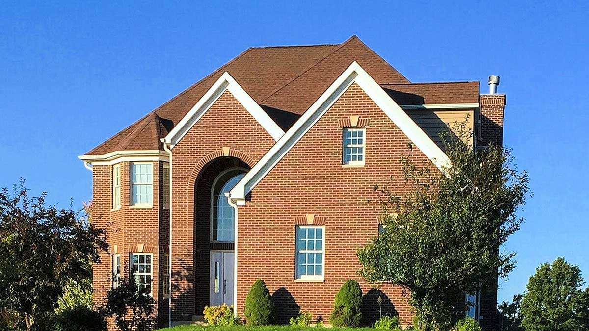 House plan exterior: Two-story brick home with prominent gables, arched entryway, and bay window.