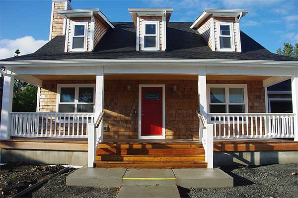 House plan exterior showing a two-story home with a covered porch, cedar shingles, and three dormer windows.