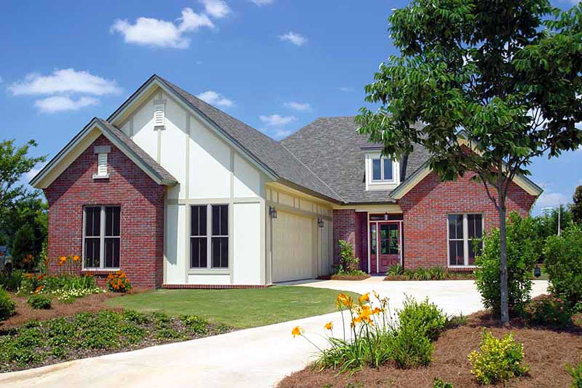 House plan exterior: Two-story brick home with gabled rooflines, dormers, white siding accents, and a two-car garage.