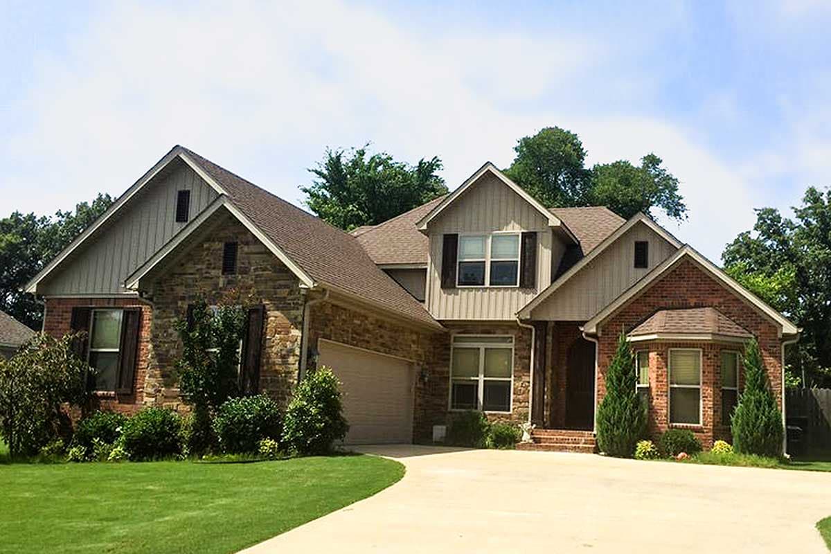 House plan exterior with brick and stone facade, dormer window, gabled rooflines, and attached garage.