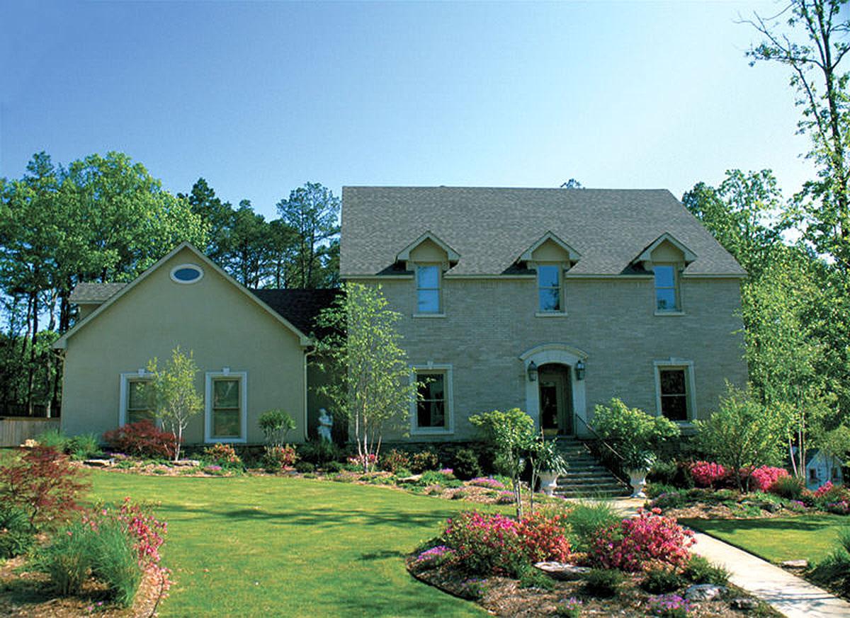 Two-story house plan exterior with brick facade, arched entryway, multiple gables, and dormer windows.