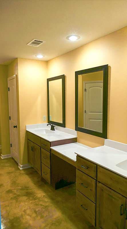 Bathroom with double vanity, white countertops, wood cabinets, and large mirrors.