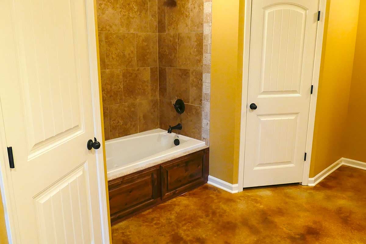 Bathroom with tiled shower walls, wooden tub surround, and two paneled doors.