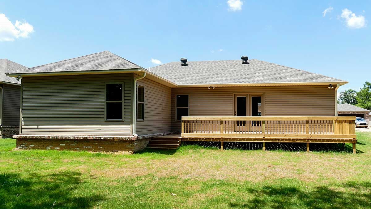 House plan exterior: single-story home with vinyl siding, a large wooden deck, and gabled roof.