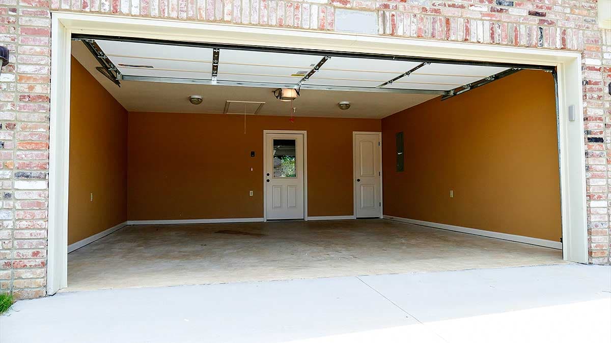 Garage interior with brick exterior, two interior doors, and an open garage door.