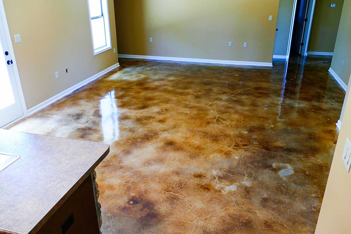 Interior view of a room with stained concrete flooring, beige walls, white trim, and a window.