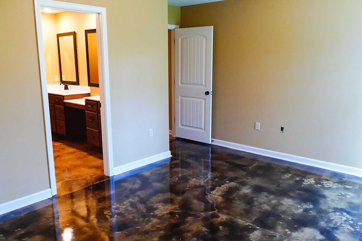 Interior view of bedroom with open doorway to bathroom featuring double vanity and a paneled door leading out.