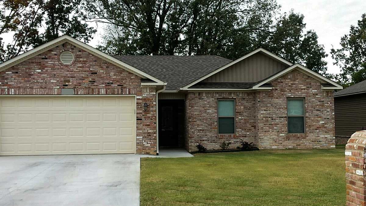 House plan exterior: Single-story brick home with a front-facing garage, gable roof, and circular vent in front gable.