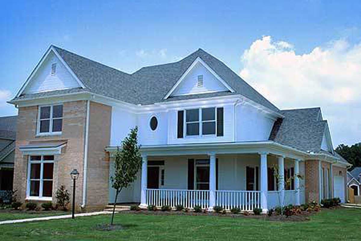 House plan exterior: two-story home with brick accents, wraparound porch, gables, and dormers.