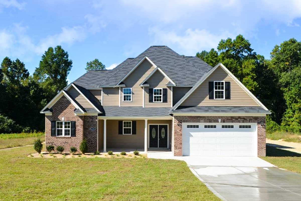 House plan exterior: Two-story home with brick and vinyl siding, covered front porch with double doors, gabled dormers, and attached two-car garage.