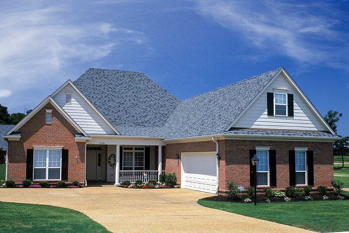 House plan exterior: Traditional brick ranch with gable dormer, covered front porch, and attached two-car garage.
