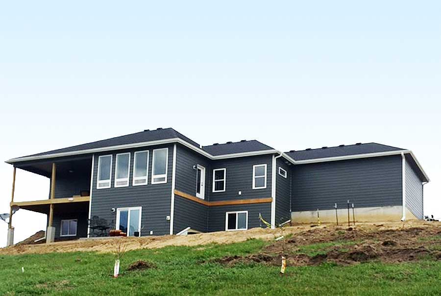 House plan exterior: Two-story dark gray siding with white trim, a covered deck, and multiple windows.