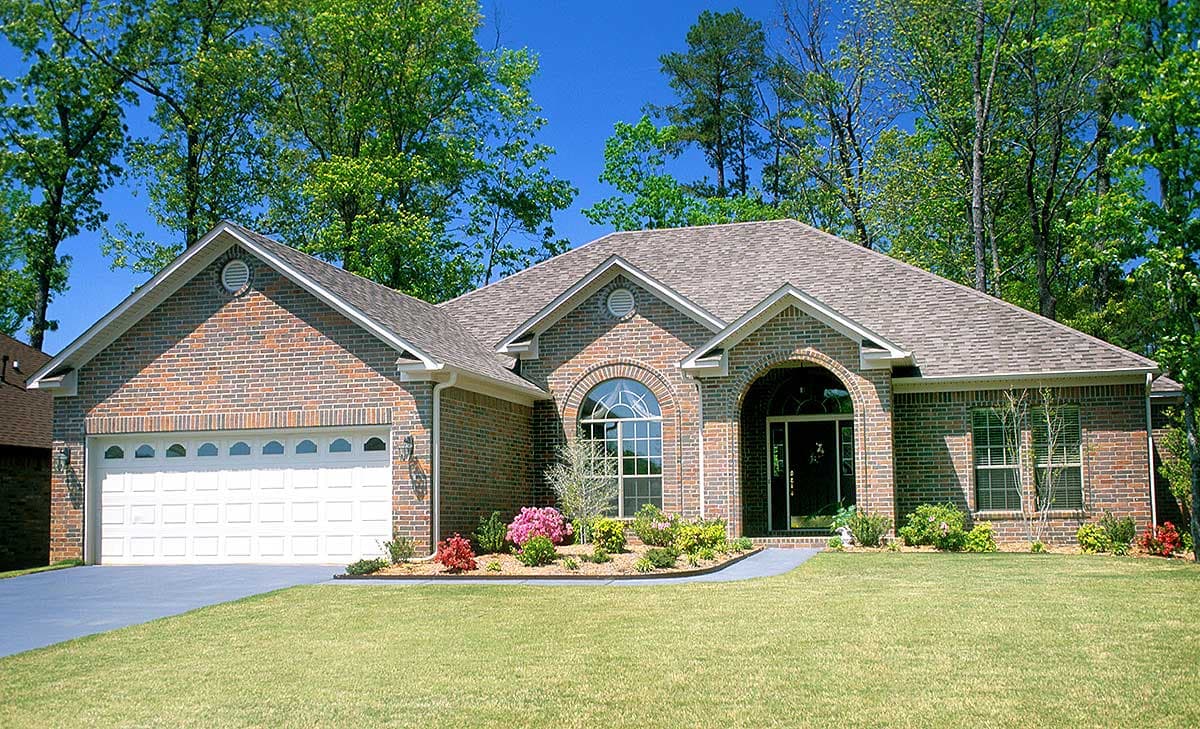 House plan exterior: Brick facade, one-story, arched entry, arched window, and attached garage.