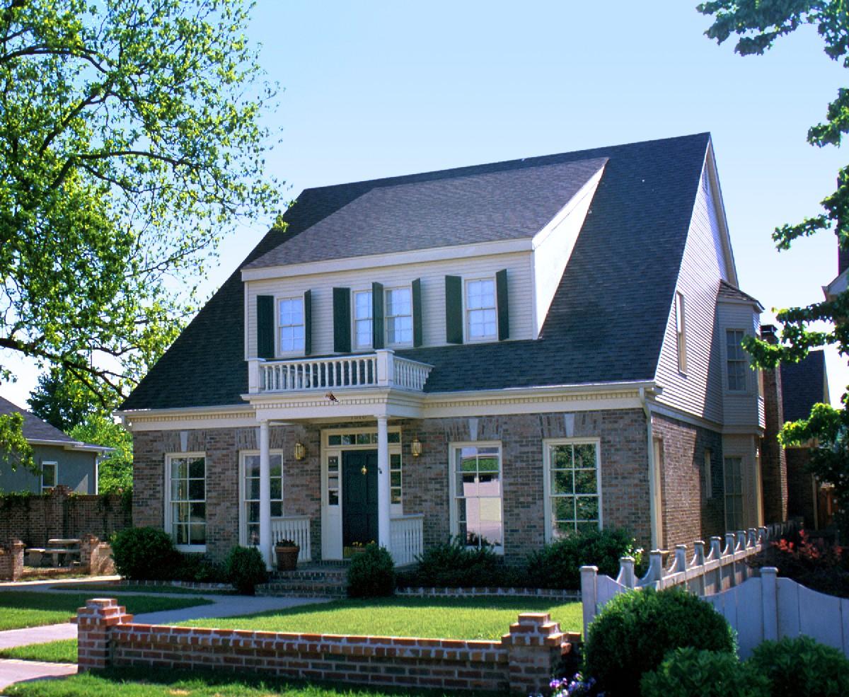 Two-story house plan exterior with brick facade, prominent dormers, white balcony, and central portico.