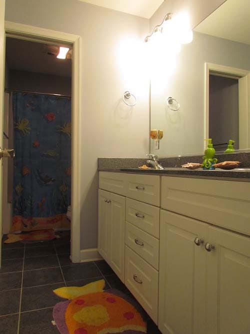 Bathroom with double vanity, granite countertop, and view into tub/shower area with a blue marine-themed shower curtain.