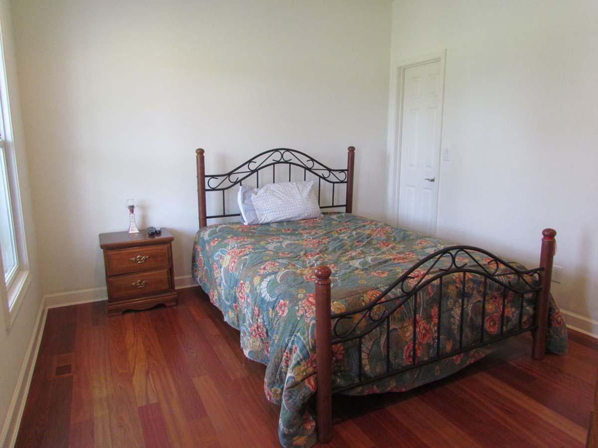 Bedroom with a queen-size bed, ornate metal headboard, wooden nightstand, and interior door.