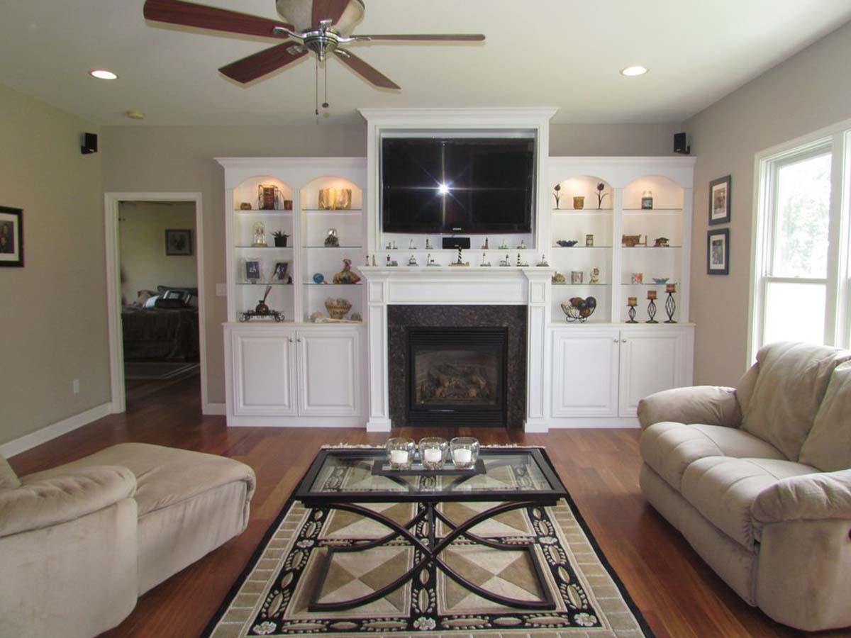 Living room with fireplace, built-in display cabinets, television, sofa, and coffee table.