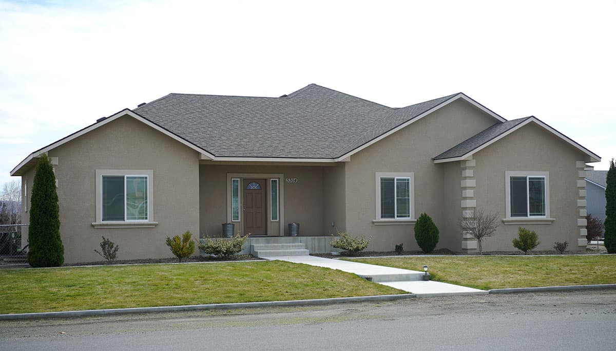 Ranch-style house plan exterior with a covered entry, multiple gables, and a stucco finish.