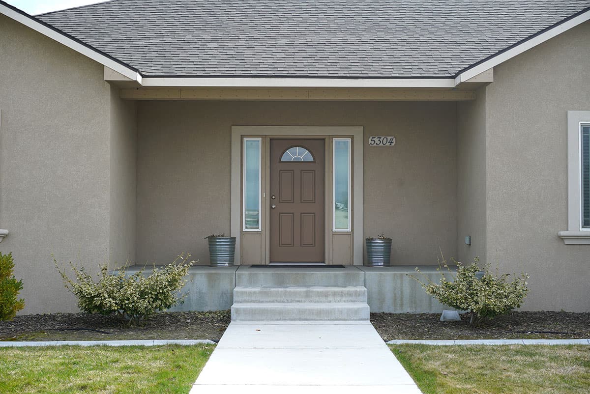 House plan exterior: Ranch style with covered entryway, arched transom door, and side windows.