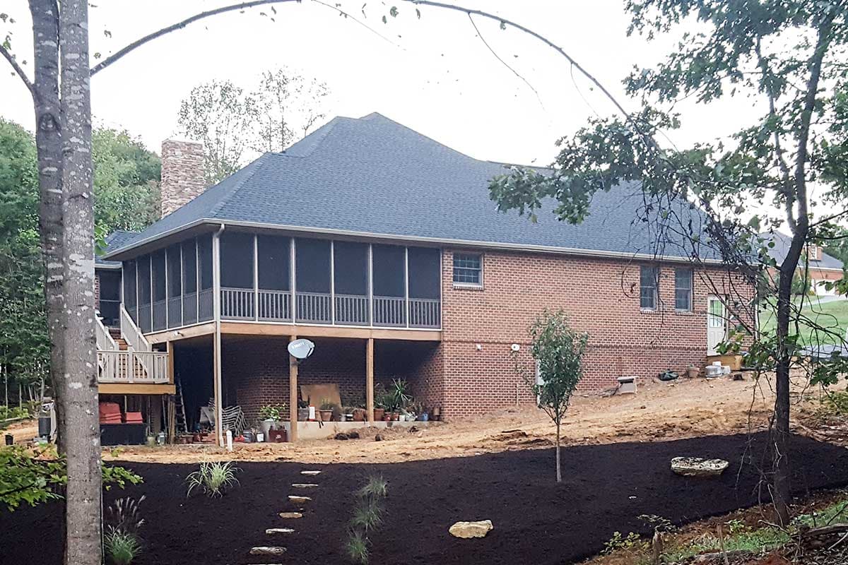 House plan exterior shows brick two-story home with large screened porch, deck, and stone chimney.