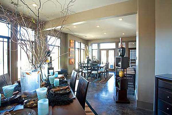 Open concept dining and living area with large windows, recessed lighting, and dark wood furniture.