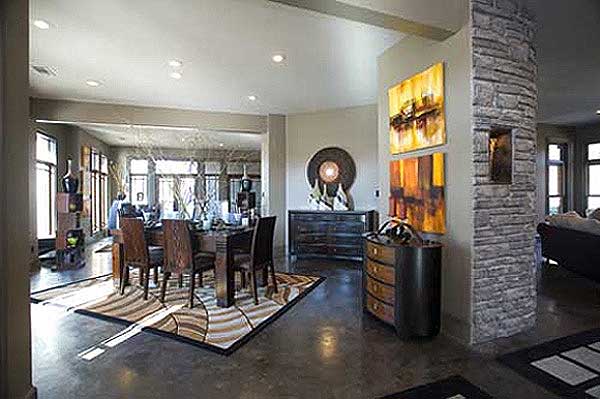 Open-concept dining and living areas with stone column, artwork, and large windows.