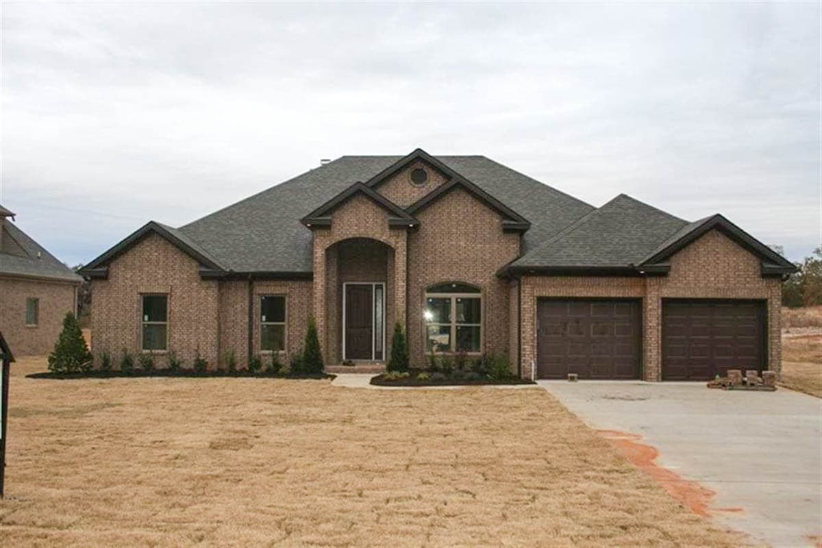 House plan exterior, one-story brick home with arched entryway, dormer, and attached three-car garage.