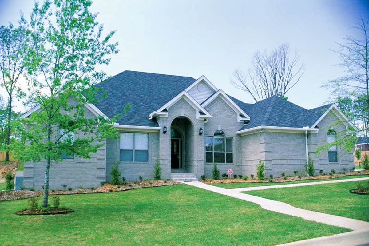 House plan exterior: Single-story brick home with arched entryway, multiple gables, and varied rooflines.